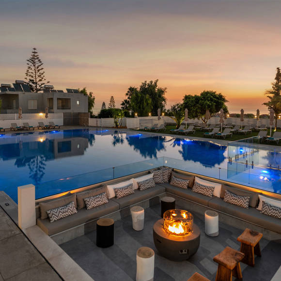 Evening pool area at Dore Hotel by Trend Hotels in Chania with cozy fire pit and illuminated water