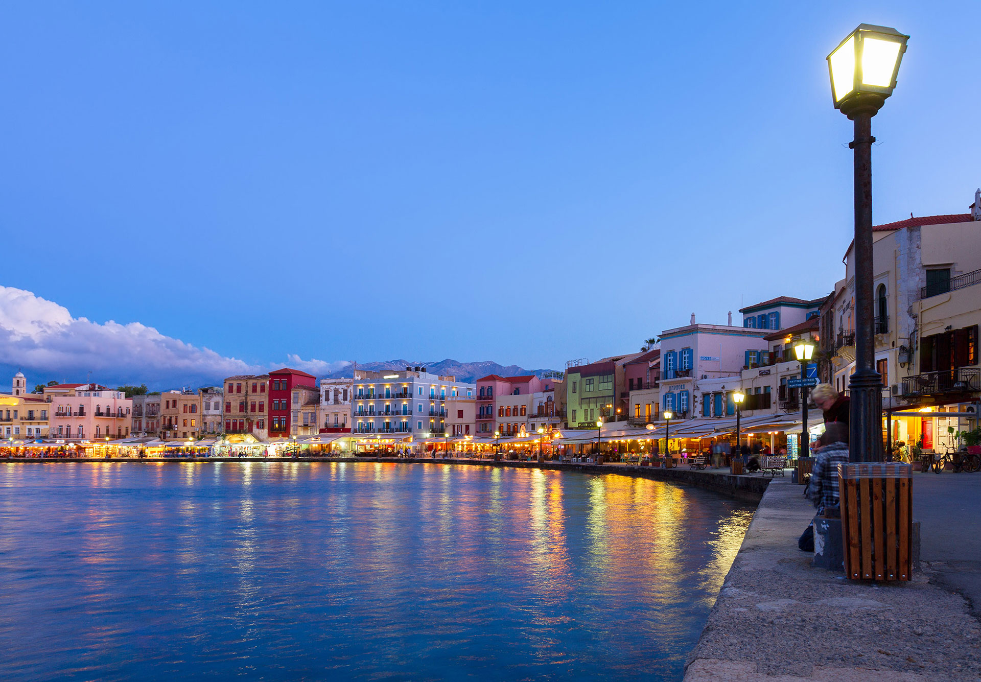 Evening view of Chania Old Venetian Harbor with colorful waterfront buildings and lively atmosphere