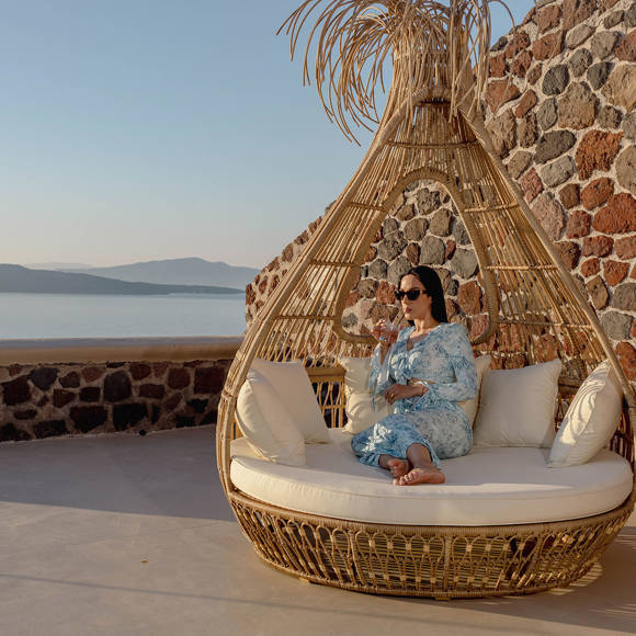 Guest relaxing on outdoor lounge chair with caldera view at Grand Ambassador by Trend Hotels in Santorini